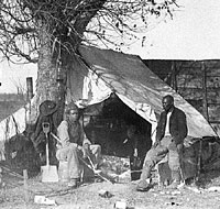 Contrabands sitting in front of an army tent