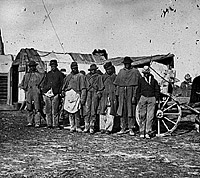This group of "Contrabands" are wearing old Union uniforms and standing near a signal tower